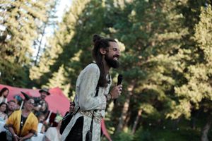 Sunny outdoor celebration with guests gathered among trees and natural scenery.