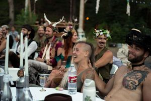 Festival attendees laugh and celebrate outdoors with decorated headpieces and casual attire.
