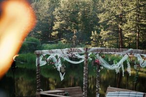 White decorative banners and bunting hang between trees in a woodland wedding setting at dusk.