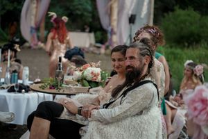 Wedding guests enjoying food and drinks at rustic outdoor tables during a celebration.