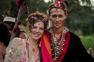 A joyful celebratory outdoor gathering with people wearing colorful floral crowns and festive attire.