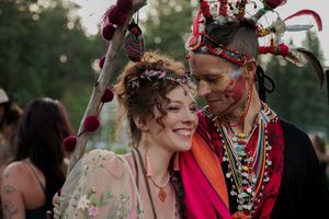 A couple in festive attire sharing a joyful moment at an outdoor celebration.