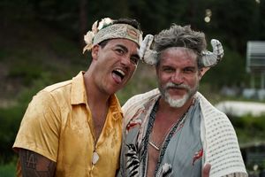 Two people in theatrical costumes share a playful moment at an outdoor event.