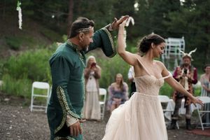 Wedding celebration with guests dancing outdoors in a forest setting.