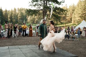 Wedding party guests celebrate during an outdoor forest reception with joyful dance moves.