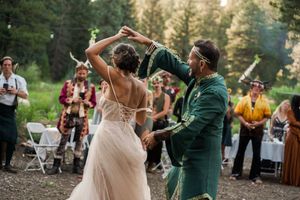 Dancing couple twirls joyfully at outdoor forest wedding reception.