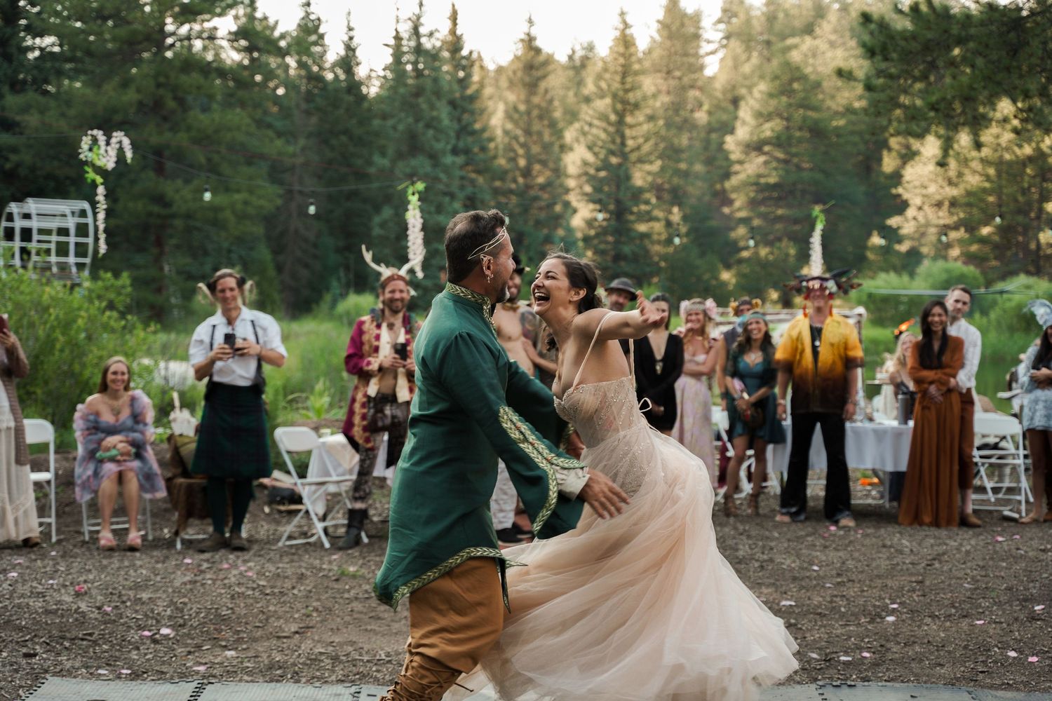 A joyful first dance celebration at an outdoor forest wedding with guests looking on.