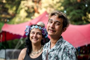 Festival-goers enjoy an outdoor celebration under a pink tent canopy.