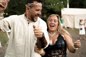 A medieval-themed celebration with dancing and laughter at an outdoor party.