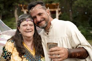 A festive outdoor celebration with participants in medieval garb sharing drinks and laughter.