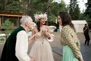 Wedding guests share laughter and conversation during an outdoor celebration with string lights.