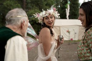 Wedding celebration outdoors with decorative tent backdrop and floral crown details.