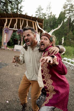 Two people in period costumes share an animated moment at a renaissance festival.