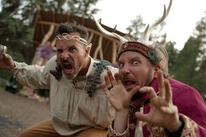 Two people in medieval costumes making exaggerated expressions and gestures at an outdoor event.