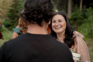 Candid laughter and joyful moments shared at an outdoor celebration in a forest setting.