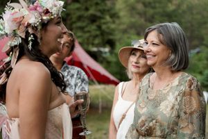 A group smiling together at an outdoor celebration with floral decorations and forest scenery.