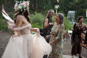 Wedding celebration in a wooded setting with guests in casual and formal attire.