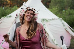 A joyful celebration in front of a white bell tent with floral decorations and string lights.