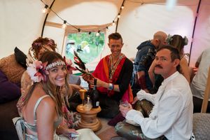 Party guests socialize under a white tent during an outdoor celebration.