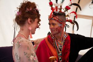 Wedding ceremony performers in colorful costumes and floral headpieces engaging in a theatrical performance.