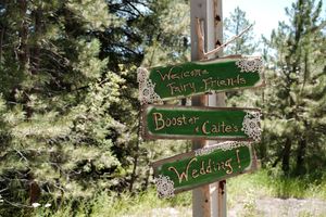 Rustic wooden directional signs for a wedding celebration mounted on wooden posts.