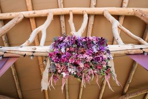 Purple and pink floral decorations adorning a wooden beam ceiling structure.