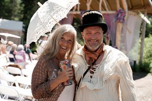 Wedding attendees in medieval-inspired costumes celebrate outdoors under sunny skies.