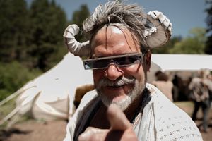 Festival attendees in medieval costumes and horned headdresses enjoying an outdoor gathering.