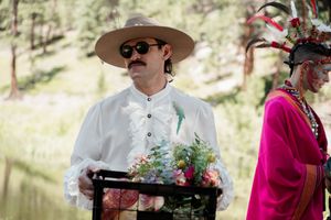 Wedding musicians in western attire performing at an outdoor ceremony in a sunny forest setting.