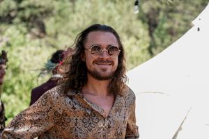 Guests enjoying an outdoor celebration under summer sunshine wearing bohemian-style clothing.