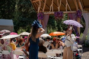 Outdoor wedding reception setup with white umbrellas and wooden pavilion in a forest setting.