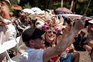 Wedding guests raise their hands in celebration during an outdoor ceremony.