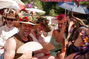 Guests celebrating at a festive outdoor gathering wearing elaborate costumes and headpieces.