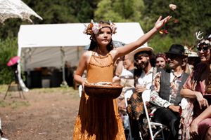 Guests in period costumes celebrate at an outdoor medieval festival under clear skies.