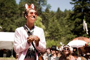 Wedding guests clap and celebrate during an outdoor forest ceremony.