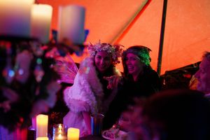 Wedding reception guests dance and celebrate under warm orange lighting and decorative ambiance.