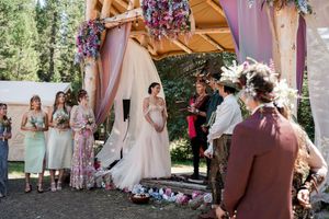 Bridesmaids in floral dresses gather at an outdoor garden wedding venue with pink decor and natural lighting.