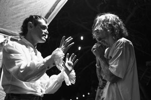 Two performers engaged in an animated black and white stage performance with dramatic hand gestures.
