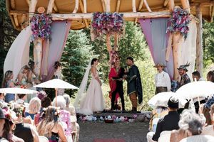 Wedding ceremony setup with wooden beams and floral decorations in a natural outdoor setting.