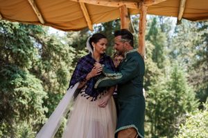 Wedding celebration with dancing couples under a canopy in a forest setting.