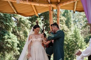 A wedding ceremony moment under a wooden canopy decorated with flowers.