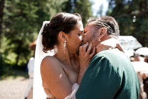 An emotional moment captured during an outdoor wedding ceremony with sunlight filtering through forest trees.