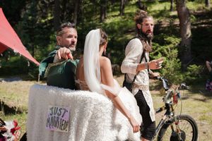 A scenic woodland wedding ceremony with bikes and whimsical decorations in the background.