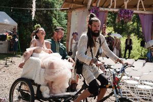 A unique wedding exit featuring a decorated tandem bicycle in an outdoor forest setting.