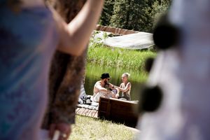 Wedding ceremony setup in a mountain forest with guests seated on white chairs.