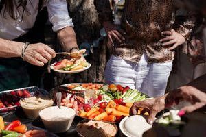 Close-up of buffet table with colorful appetizers and dishes at outdoor reception.