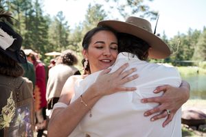 Joyful embraces shared during an outdoor celebration with mountains in the background.