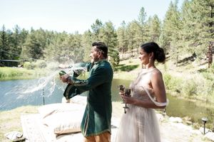 Outdoor forest wedding ceremony with scenic lake and mountain backdrop.