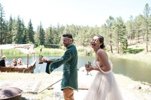 Wedding party celebrating near a scenic lake surrounded by pine trees.