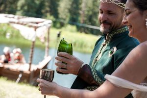 Friends sharing drinks and toasting at an outdoor celebration near a lake.
